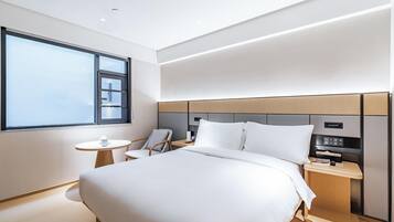 A modern hotel room with a large bed, a bedside table, a chair, and a window.