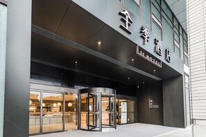 Ingresso di un hotel con una porta girevole, ampie vetrate e una segnaletica che indica il nome dell'hotel.