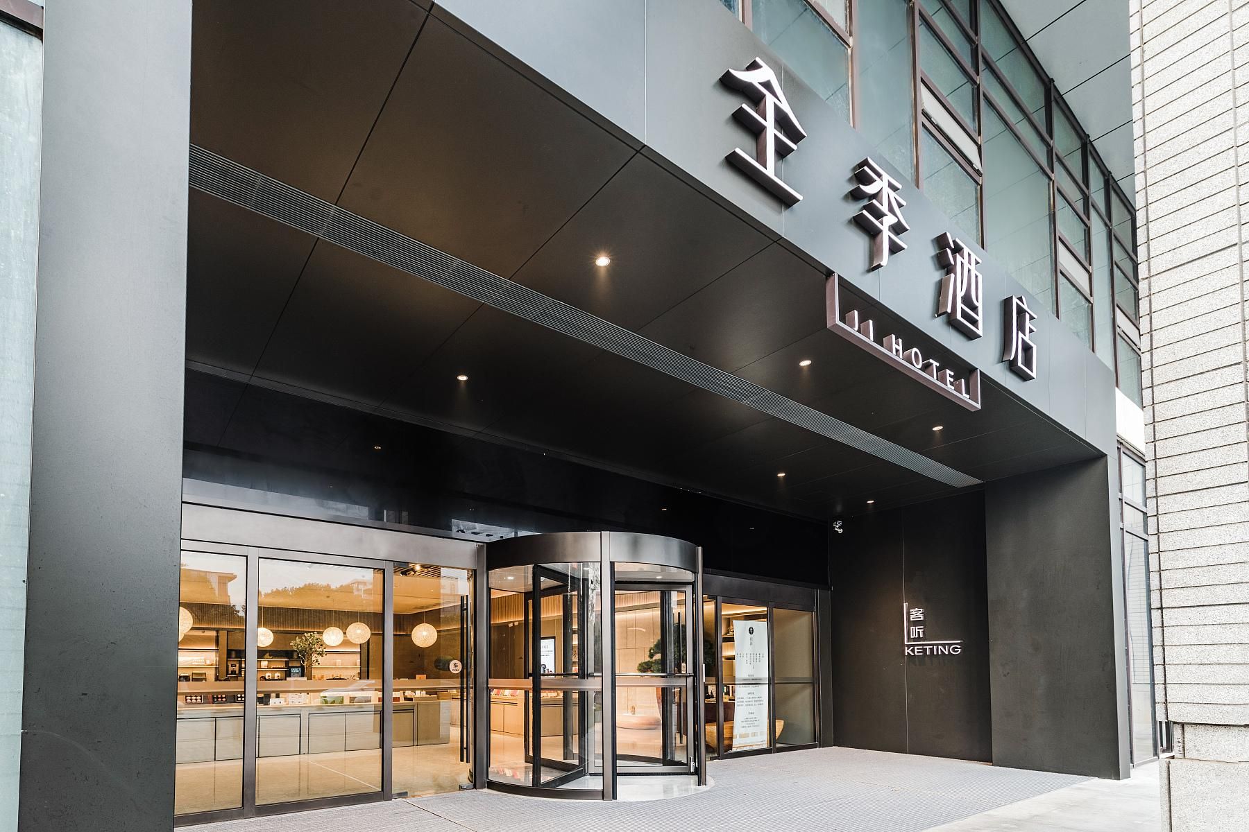 A hotel entrance with a revolving door, large glass windows, and a sign indicating the hotel name.