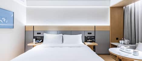 A modern hotel room with a large bed, bedside tables, a desk, and a view of the city.