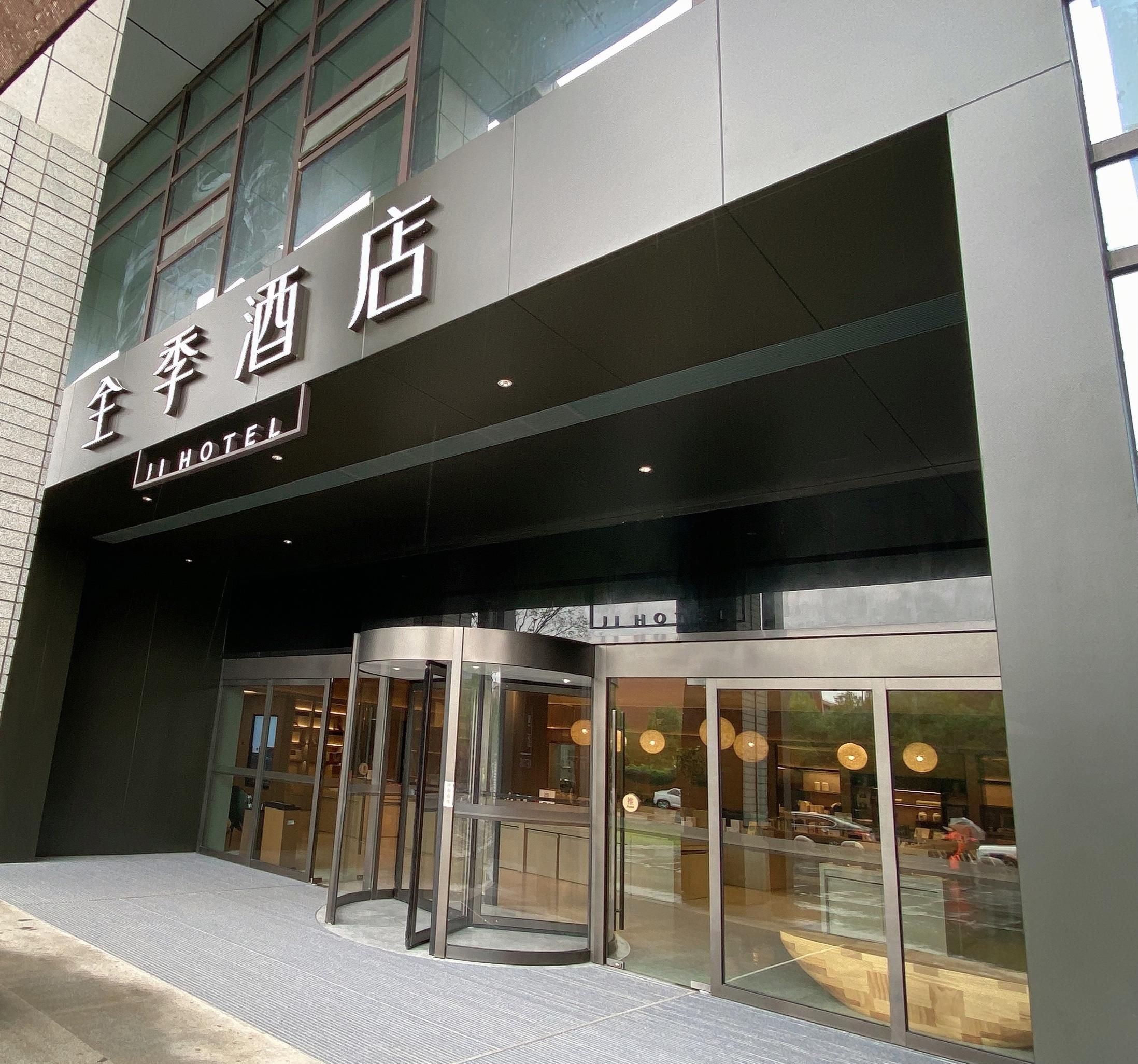 A hotel entrance with a revolving door, glass facade, and signage in a foreign language.