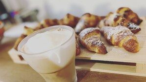 Un vaso de café helado y una tabla de madera con croissants.