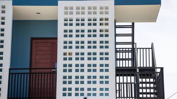 Ein Gebäude mit blauer Fassade, einer braunen Tür und einem weißen Gitterwerk.