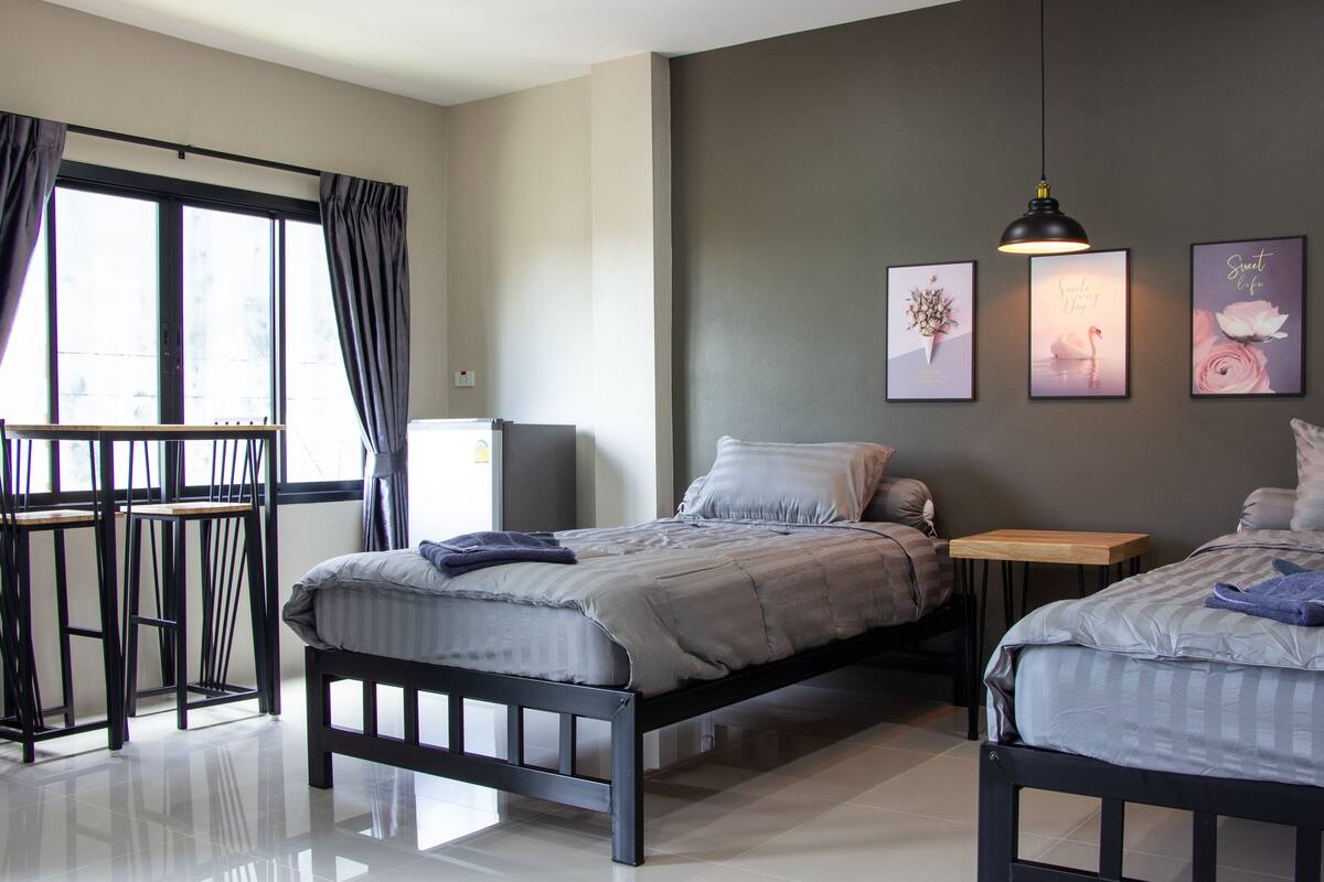 A modern bedroom with two beds, a desk, and a chair.