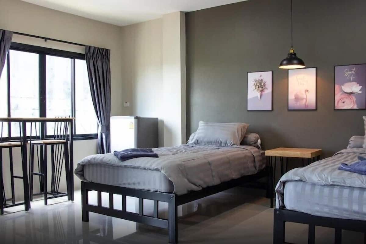 A modern bedroom with two beds, a balcony, and artwork on the wall.