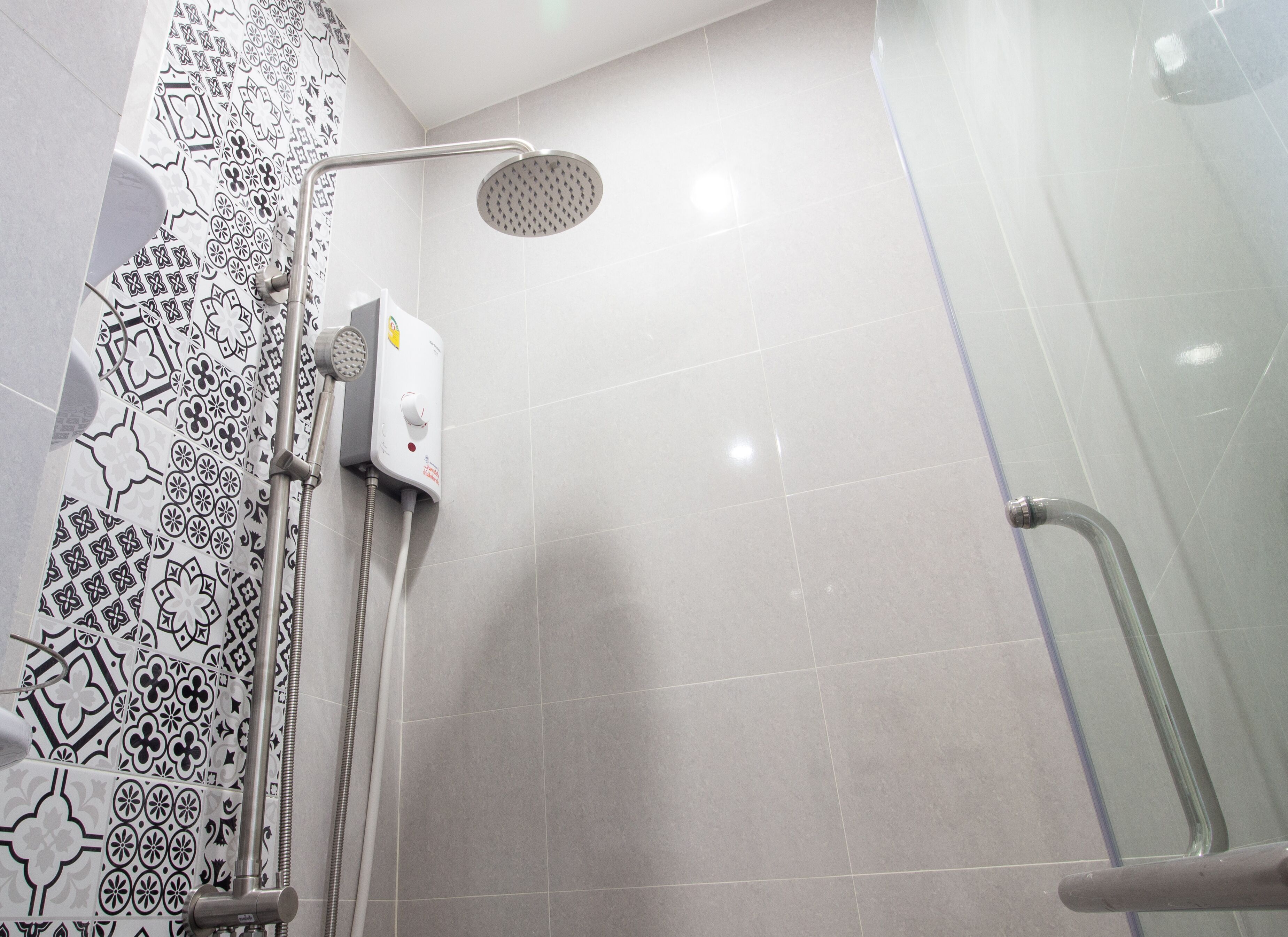 A shower area with a handheld showerhead, a wall-mounted control panel, and a glass-enclosed shower stall.