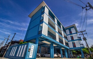 Un edificio de varios pisos con una decoración azul y blanca, que cuenta con balcones y un área de estacionamiento techada.