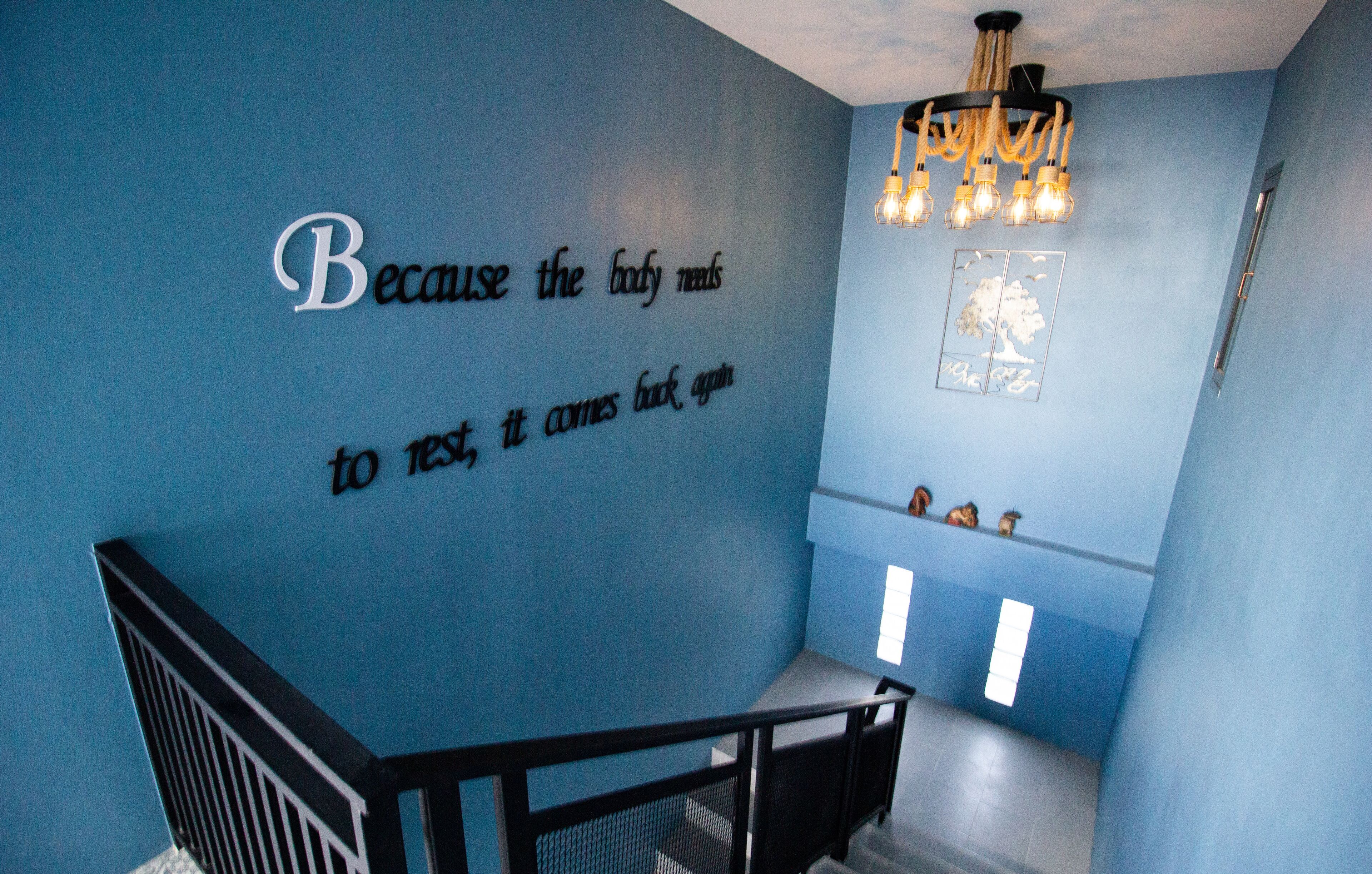 A room with a blue wall, a baby crib, and a chandelier.