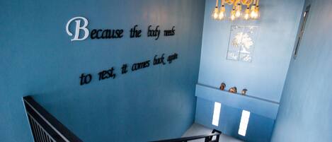 A room with a blue wall, a baby crib, and a chandelier.