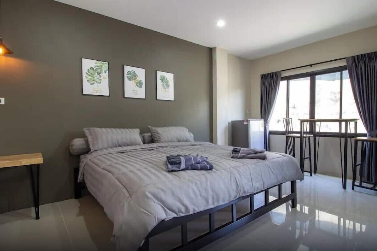 A modern bedroom with a bed, a desk, a chair, and a balcony with curtains.