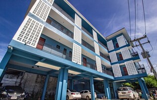Un edificio de varios pisos con balcones y una zona de estacionamiento techada.