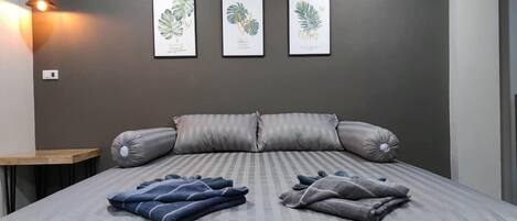 A bedroom with a bed, grey striped pillows, and three framed botanical prints on the wall.