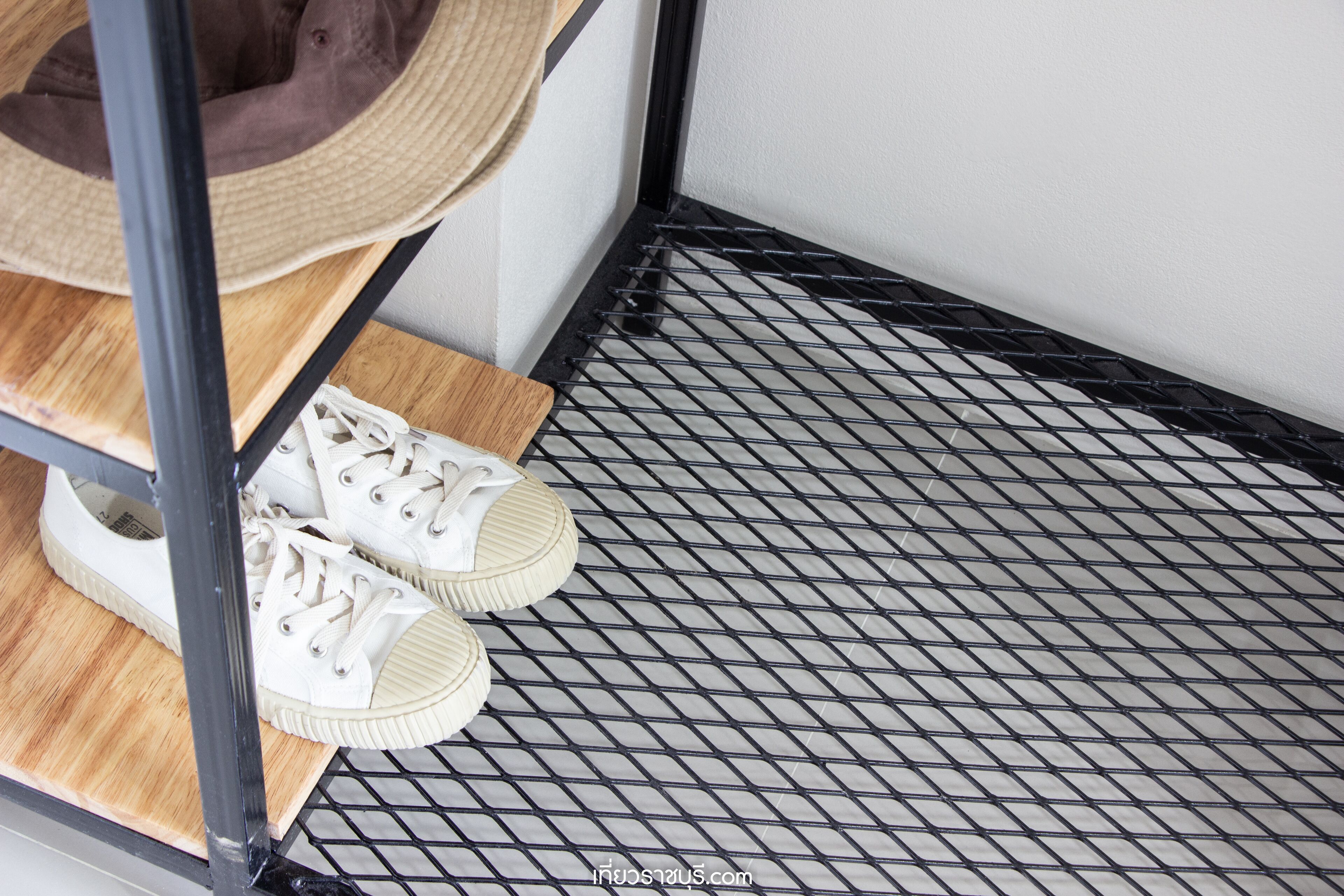 Un par de zapatillas blancas sobre una plataforma de madera con suelo de rejilla metálica negra.