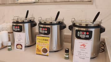 Three electric pressure cookers on a kitchen counter with labels and a small bottle of seasoning.