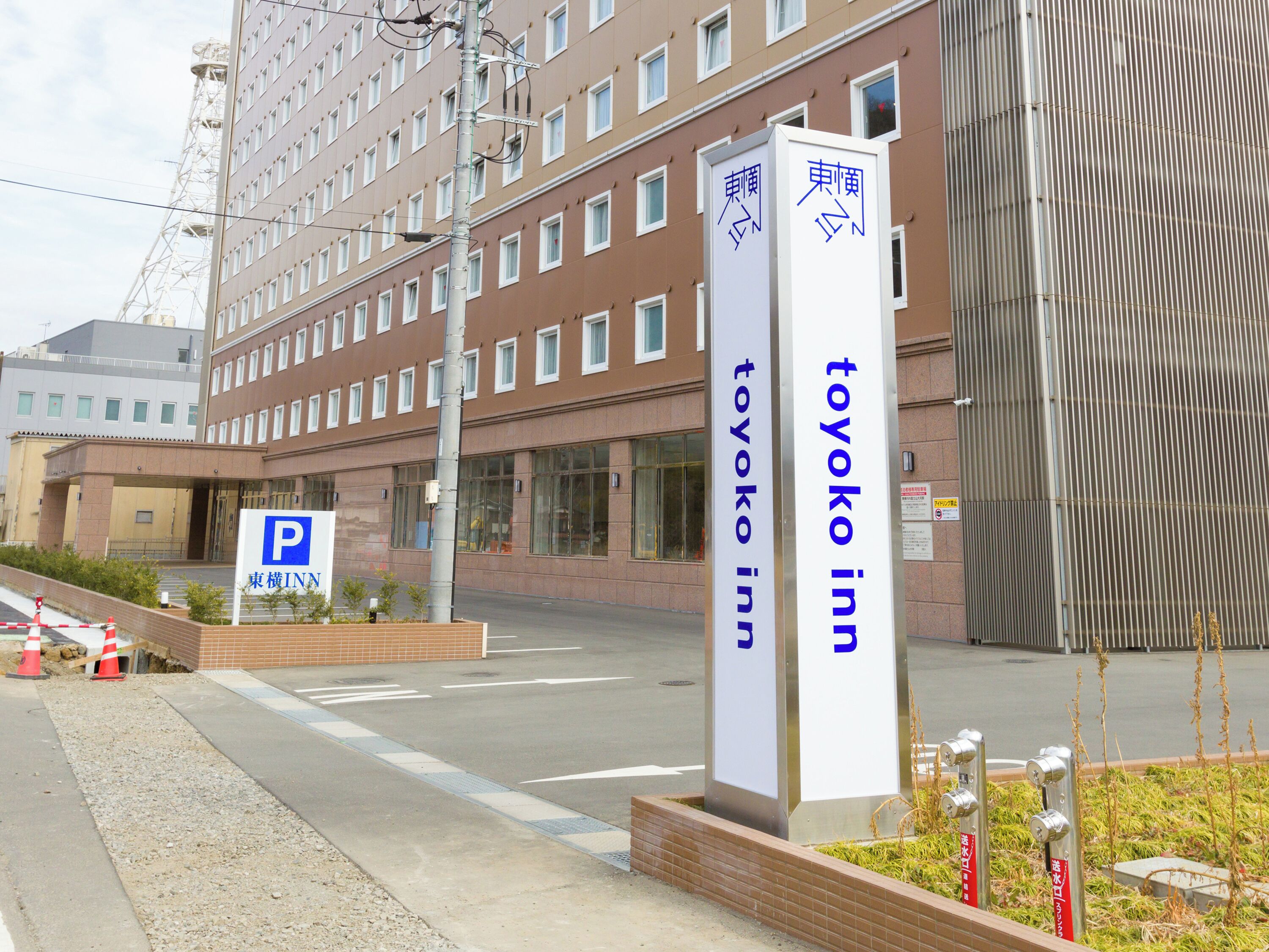 Um edifício com placa indicando 'Toyoko Inn' e sinal de estacionamento.