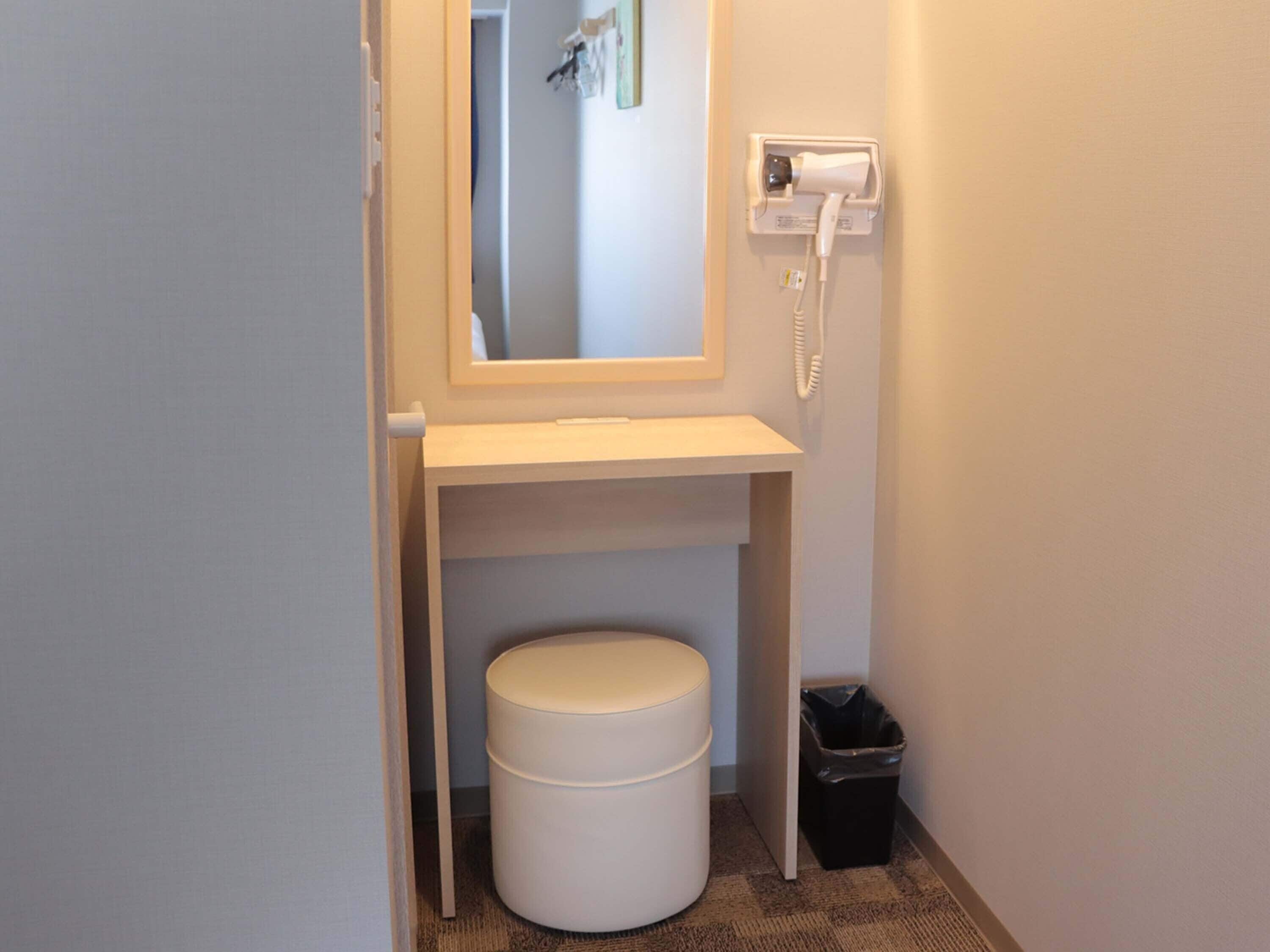 Een kleine badkamer met een wit wastafel, een spiegel, een telefoon en een prullenbak.