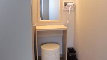 Een kleine badkamer met een wit wastafel, een spiegel, een telefoon en een prullenbak.
