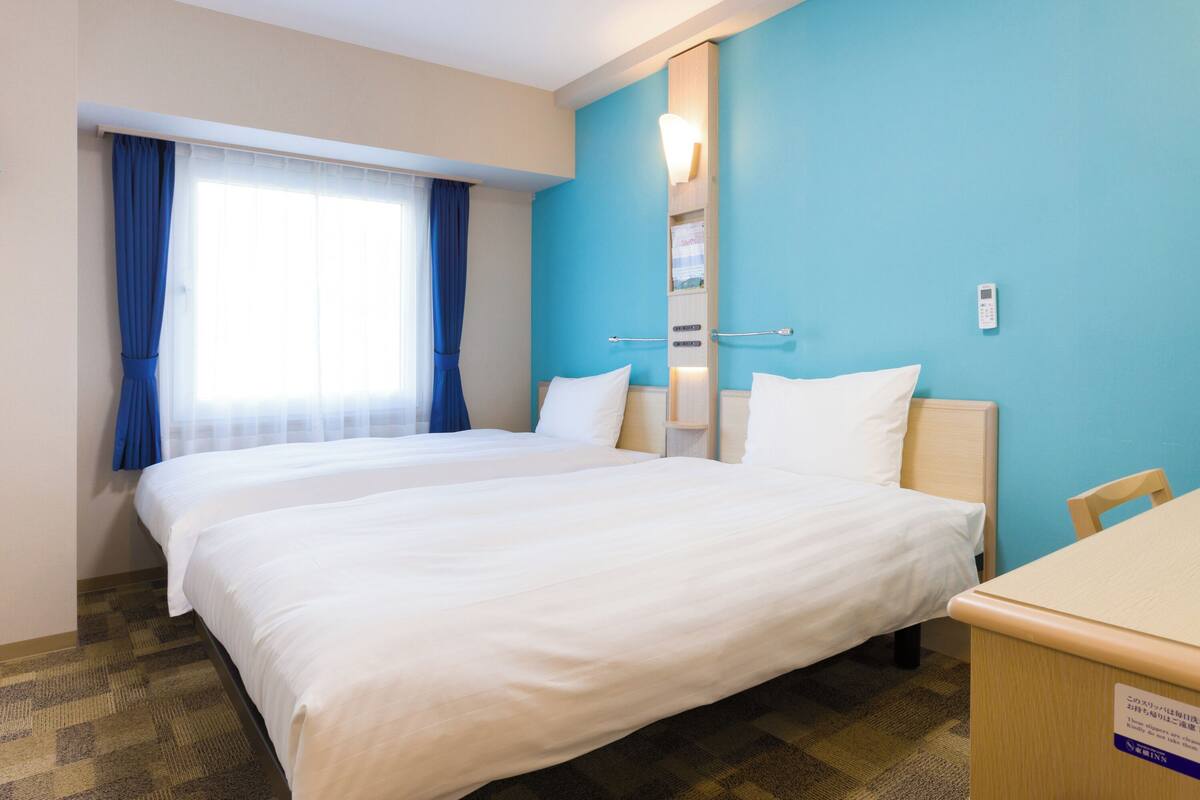 Una habitación de hotel con una cama grande, un escritorio y una ventana con cortinas.