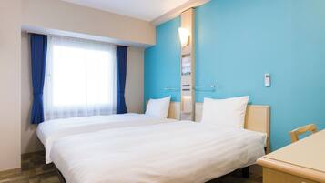 A hotel room with a large bed, a desk, and a window with curtains.