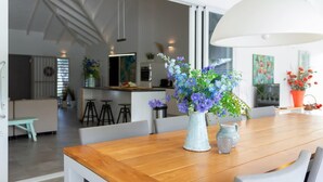 Un comedor con una mesa de madera, un jarrón de flores y una lámpara colgante.