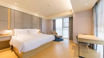 A modern hotel room with a large bed, a desk, and a chair.