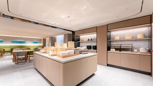 Un moderno vestíbulo de hotel con un mostrador de recepción central, zona de estar y una kitchenette.