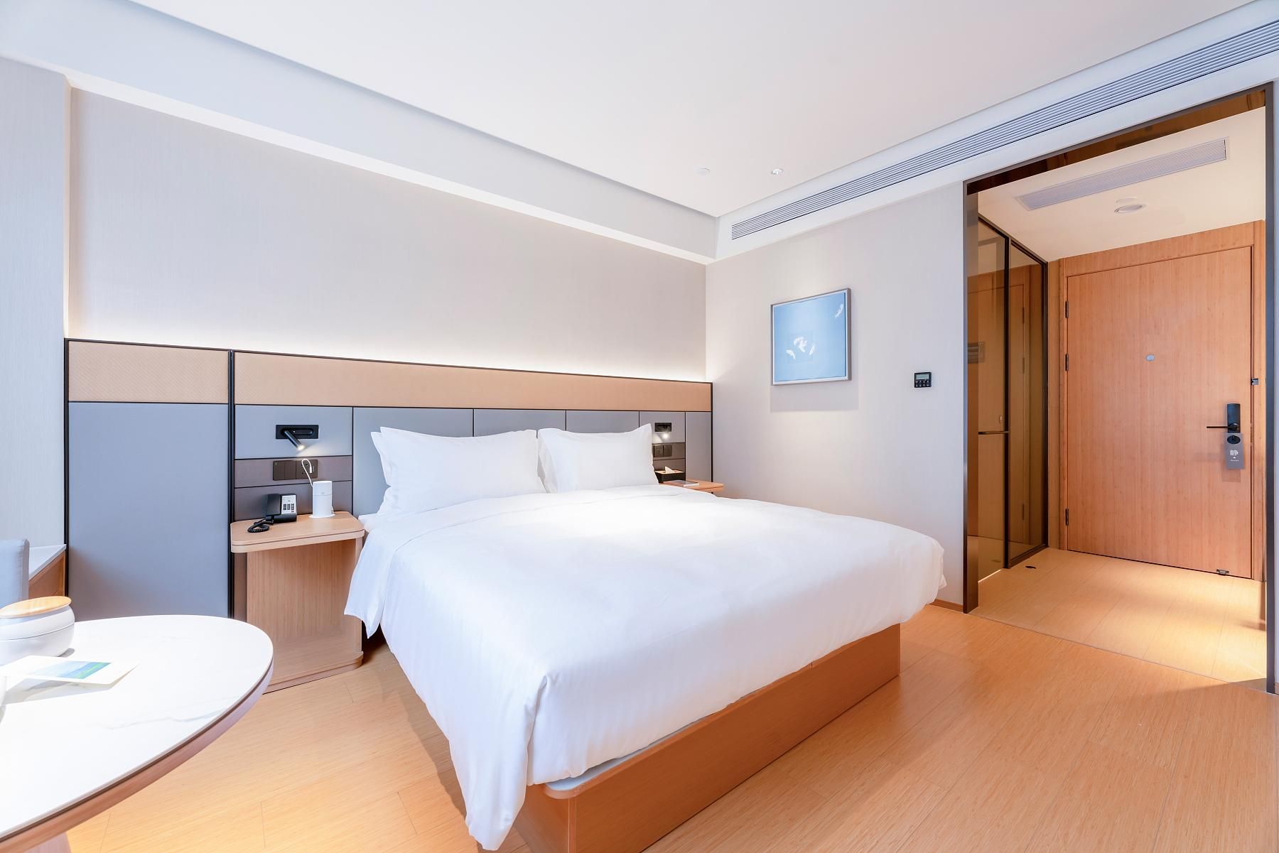 A modern hotel room with a large bed, a desk, and a chair.