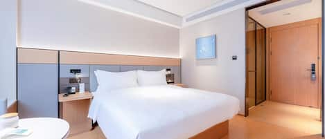 A modern hotel room with a large bed, a desk, and a chair.