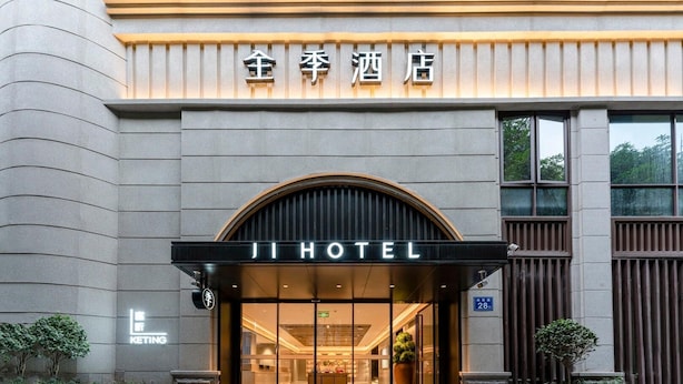 La entrada del Ji Hotel, con una fachada moderna, puertas de cristal grandes y un letrero que indica el nombre del hotel.