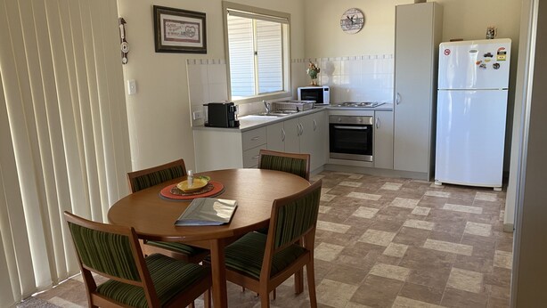 Una cocina compacta con una mesa de comedor, sillas, un refrigerador y un microondas.