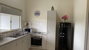 Cocina compacta con lavamanos, microondas, horno y refrigerador negro.
