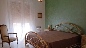 A bedroom with a bed, a chair, a nightstand, a lamp, and a window with curtains. - House of 170 sq. m., 700 m. from the center of Rosolini (Rosolini)