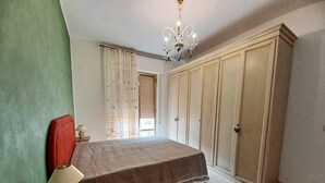 A bedroom with a bed, a nightstand, a lamp, a chandelier, a wardrobe, and a window with curtains. - House of 170 sq. m., 700 m. from the center of Rosolini (Rosolini)
