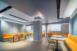 A modern interior with seating areas, tables, and a central pillar. - Hanting Hotel (Zhengzhou)
