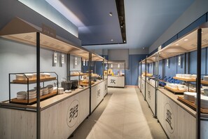 A corridor with multiple food stations, each with a wooden counter and glass display cases. - Hanting Hotel (Zhengzhou)