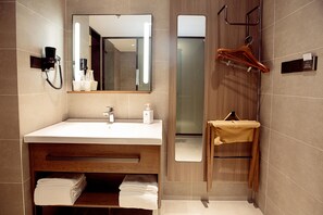 Un baño moderno con un espejo grande, un lavabo y un perchero para toallas.