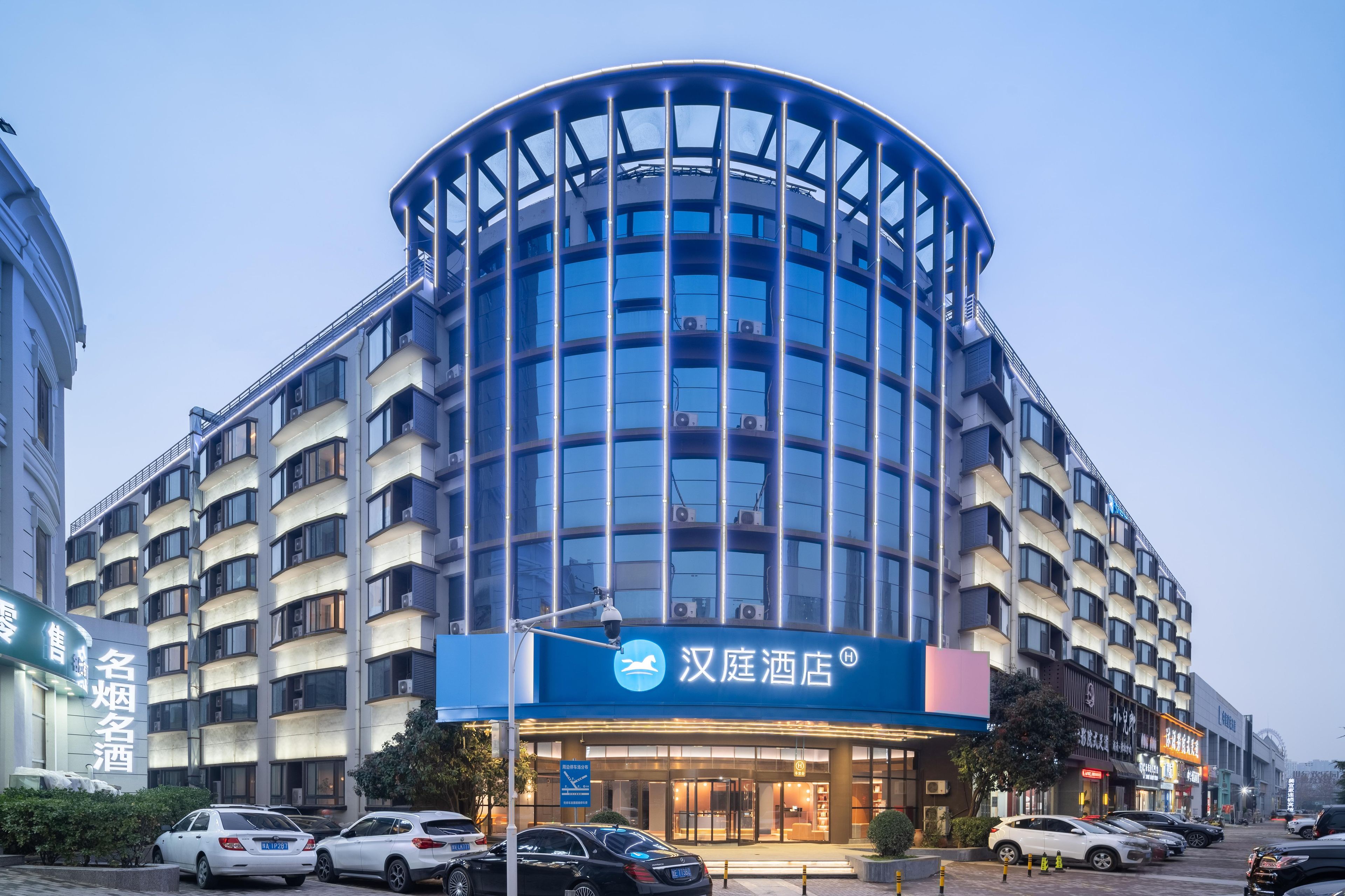 A modern hotel with a curved facade, multiple balconies, and a prominent signage.