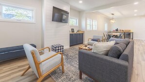 A spacious living area with a sofa, armchair, and a television mounted on the wall. - A Liberty Haven - 2 blocks from South Beach, (South Haven)