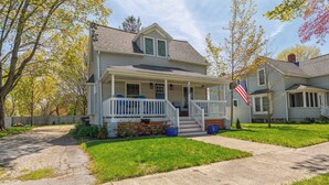 A two-story house with a front porch, a small front yard, and a visible American flag. - A Liberty Haven - 2 blocks from South Beach, (South Haven)