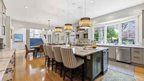 A modern kitchen with a central island, pendant lighting, and large windows.