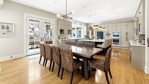 A modern kitchen with a central island, wooden flooring, and a dining area with wicker chairs.