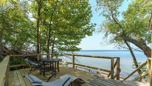 A wooden deck with a table and chairs overlooking a body of water.