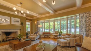 A spacious living room with a fireplace, large windows, and comfortable seating.