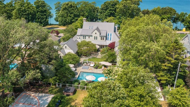 A large house with a swimming pool, surrounded by trees and a view of the ocean.