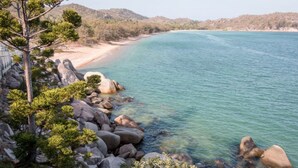 Kystlandskab med klart turkis vand, en sandstrand og klippeformationer.