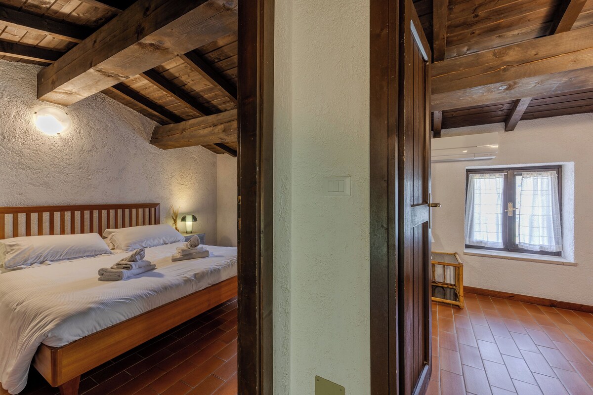 Un dormitorio con cama de madera, lámpara de noche y ventana con cortinas.