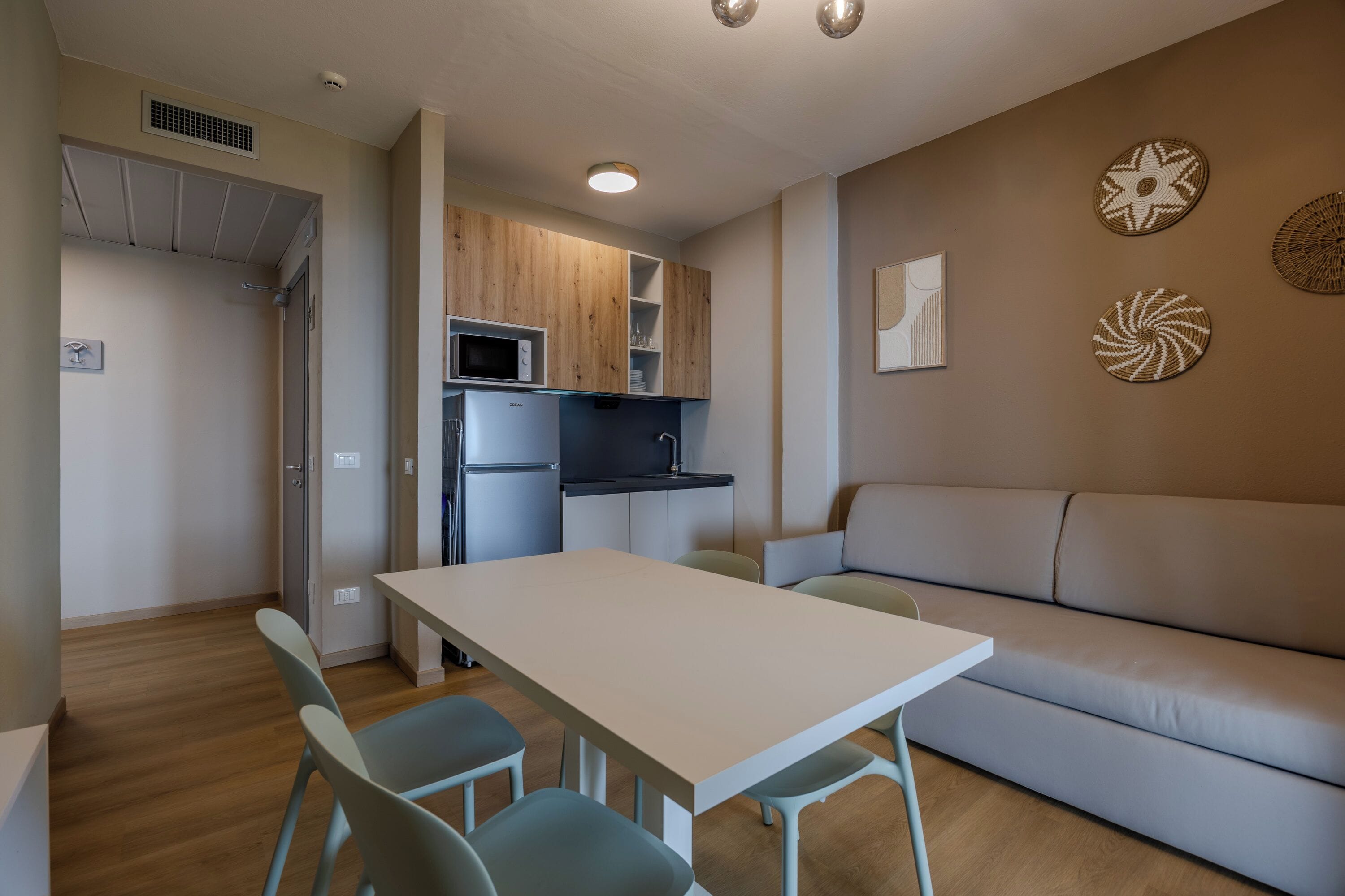 A compact living space with a kitchenette, a dining area with a table and chairs, and a sofa.