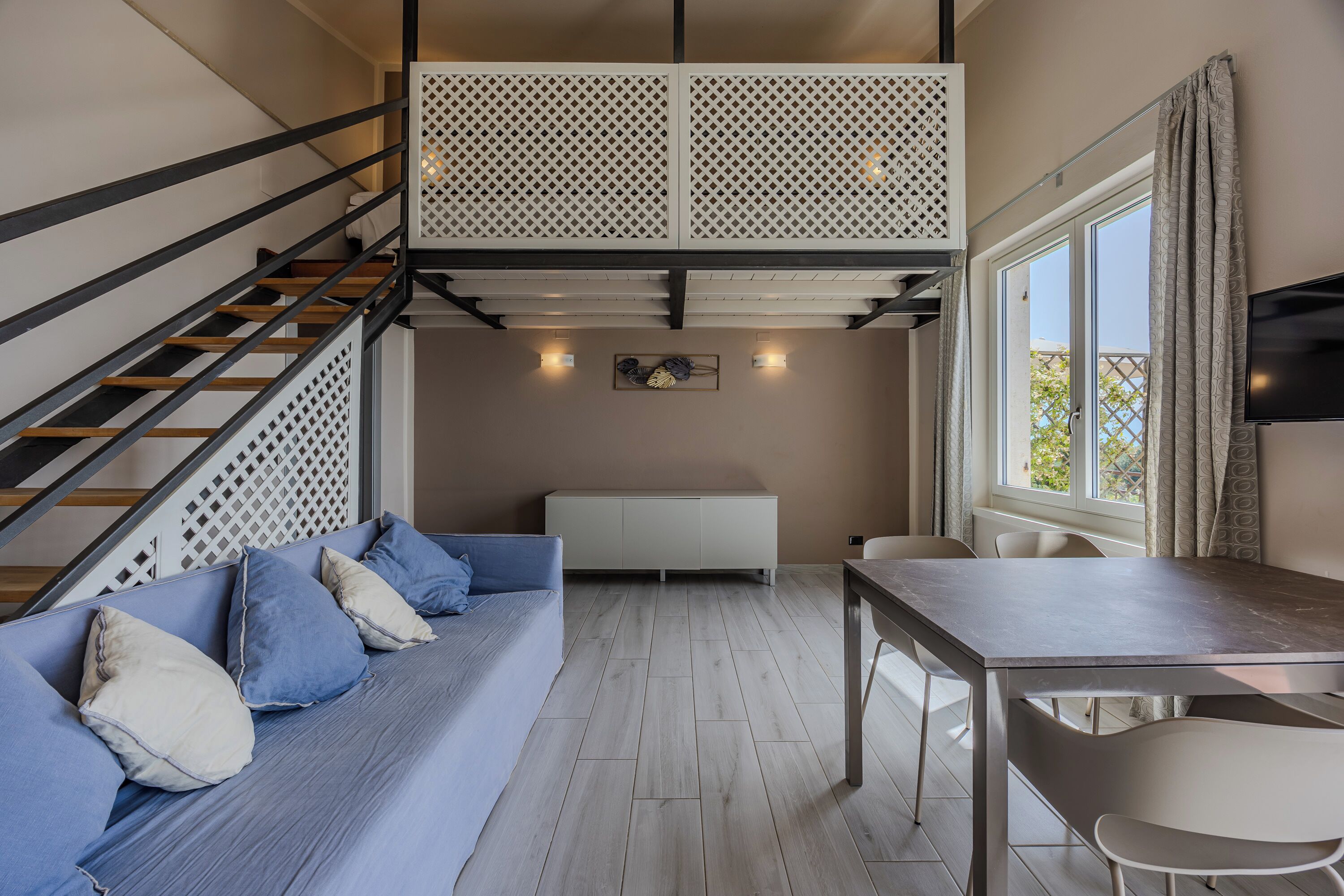 A modern room with a sofa, a table, and a staircase.