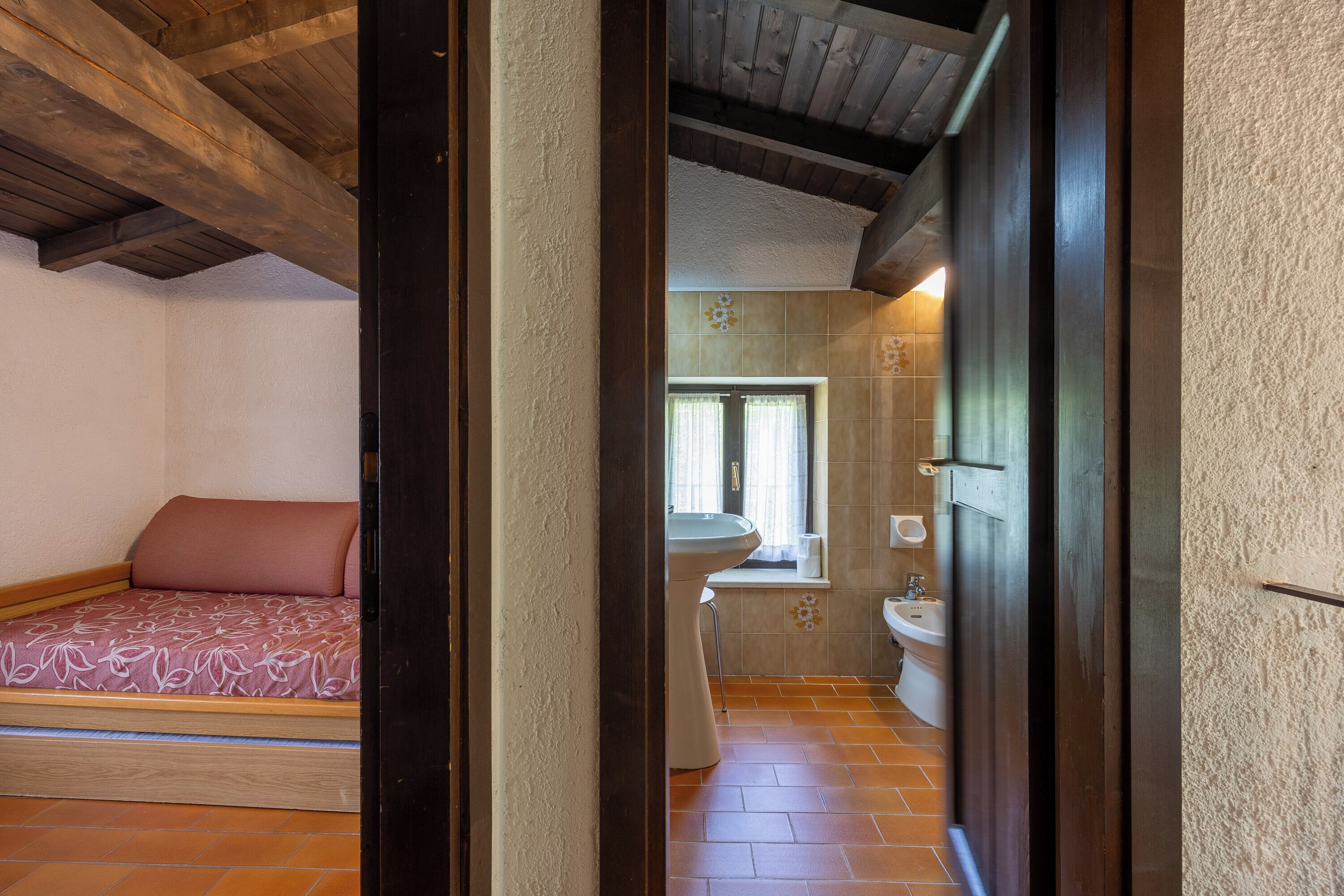 A bedroom with a bed, a window, and a bathroom with a sink and toilet.