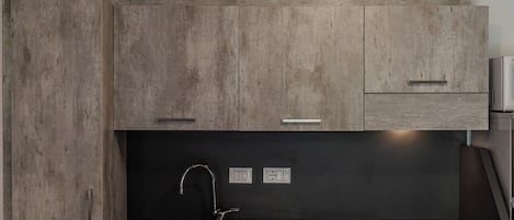 A modern kitchen with wooden cabinets, a black countertop, stainless steel sink, and a built-in stove.